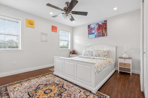 a bedroom with a white bed and a ceiling fan at Surrey Two Bedroom Suite with Pool Access in Surrey