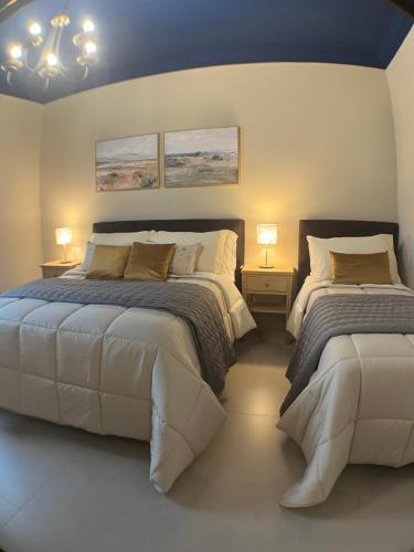 a bedroom with two beds and two lamps and a blue ceiling at Harmony Suite in Aprilia