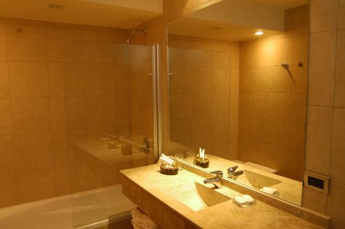 y baño con ducha, lavabo y bañera. en Virgo Hotel & Spa en Las Lenas