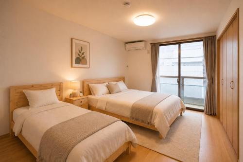 two beds in a room with a window at SaiKa 隠れ家 in Saikamachi