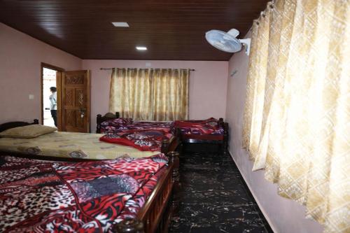 a room with three beds and a window at Peak Homestay in Kalasa