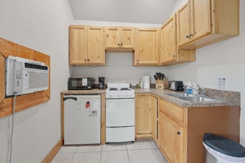 a kitchen with wooden cabinets and a white appliance at Cozy 1BR Mountain View Studio with Fireplace &Deck in Fort Collins