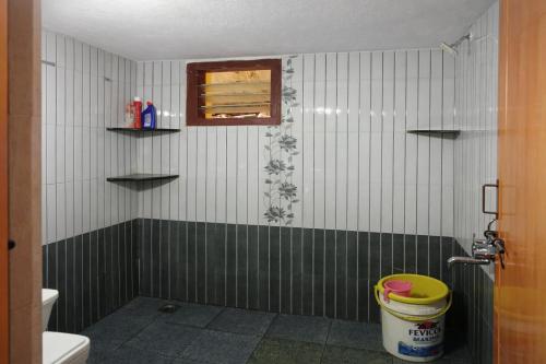 a bathroom with a toilet and a window and a bucket at Aroli Homestay in Kalasa