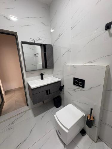 a white bathroom with a toilet and a sink at Appartement 2 chambres in Cotonou