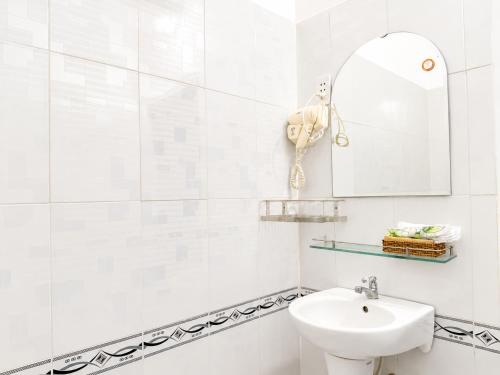 a white bathroom with a sink and a mirror at The Red Hotel Côn Đảo in Con Dao