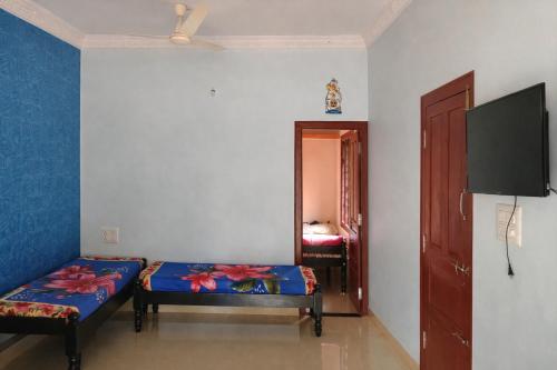 a room with two beds and a flat screen tv at Aroli Homestay in Kalasa
