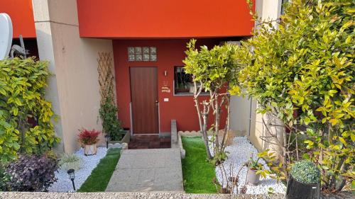 a house with a red door and some plants at Aloha Pool Apartment - Free Parking - Sirmione in Desenzano del Garda