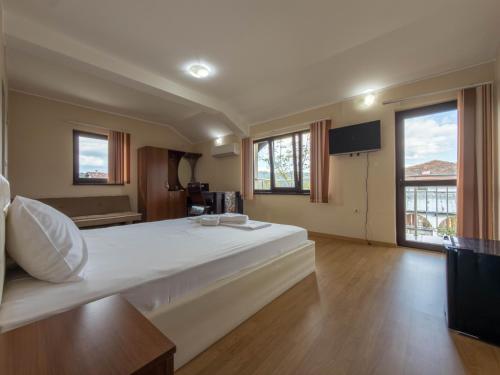 a large white bed in a room with windows at Къща за гости Sunrise - Батак in Batak