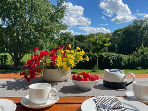 a table with cups and a bowl of strawberries and flowers at Appartment Schafstall - am Unstrutradweg in Wundersleben