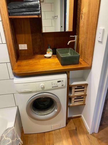 a washing machine under a counter with a sink at Kingfisher Cottage in Masterton