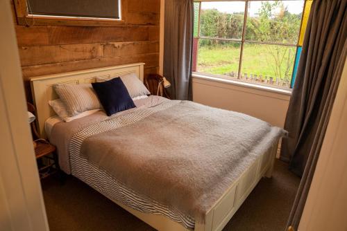 a bed in a room with a window and a bed sidx sidx sidx at Kingfisher Cottage in Masterton