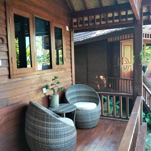 a porch of a house with wicker chairs and a table at Gecko Lodge in Tetebatu