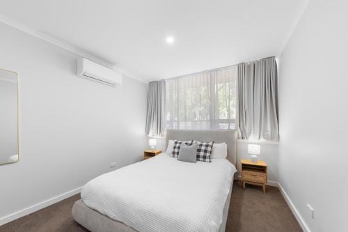 a white bedroom with a bed and a window at 3 Bedroom City Apt, Big Yard & Park Views - Sleeps 7 in Adelaide