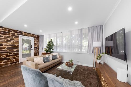 a living room with a couch and a tv at 3 Bedroom City Apt, Big Yard & Park Views - Sleeps 7 in Adelaide