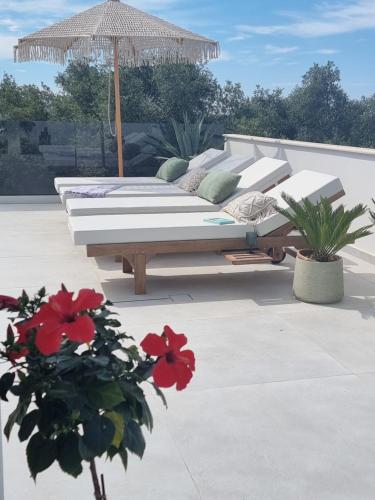 a bed on a patio with an umbrella and flowers at Villa Westwood in Parga