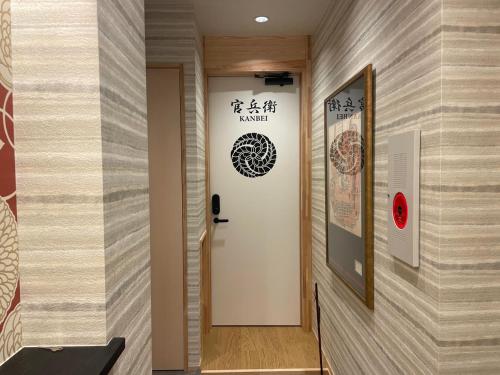 a hallway with a door with a sign on a wall at Besso城前 in Himeji