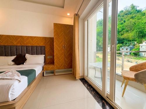 a bedroom with a bed and a large window at Hotel Mahadev Tapovan in Rishīkesh