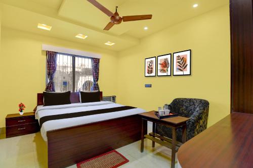 a bedroom with a bed and a chair and a table at Super Hotel O Chittaranjan Railway Station Formerly Khalsa Lodge in Āsansol