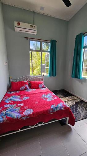 a bedroom with a bed with a red comforter at Homestay D'Bunohan in Tumpat