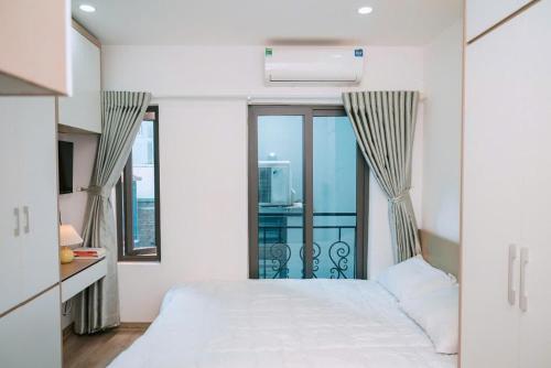 a bedroom with a white bed and a balcony at Auri House in Hanoi