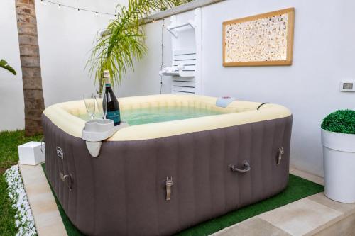 a hot tub in a backyard with a bottle of wine at Alicam in Uggiano la Chiesa