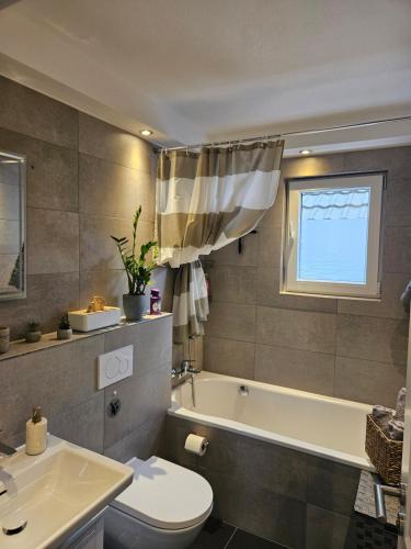 a bathroom with a tub and a toilet and a sink at Ferienwohnung Elya Gartenparadies nahe Events, Outlet und Spa in Bad Münstereifel