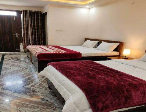 a hotel room with two beds with red covers at Shri Ved Vrinda Dham Aashram in Chhatikara