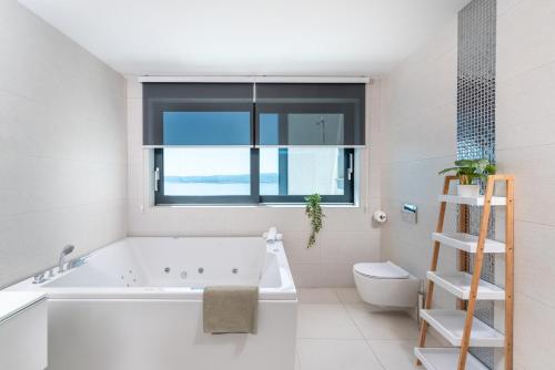 a bathroom with a tub and a toilet and a window at Villa Twins in Crikvenica