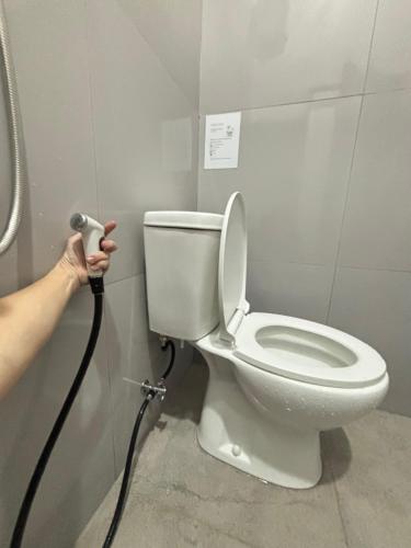 a person is washing a toilet in a bathroom at Lovisya Residence in Jakarta