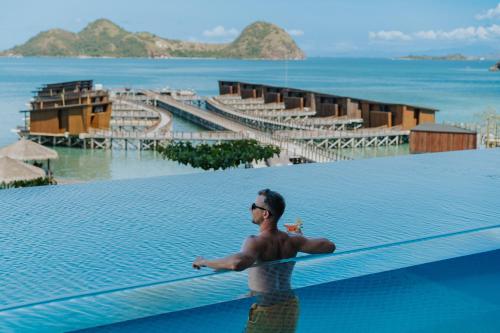 a man standing on the edge of a swimming pool at Katamaran Hotel & Resort Komodo in Labuan Bajo
