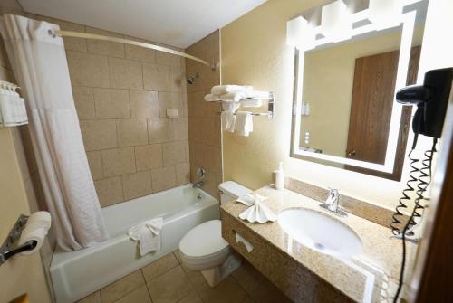 a bathroom with a sink and a toilet and a mirror at Super 8 by Wyndham Clive IA in Clive