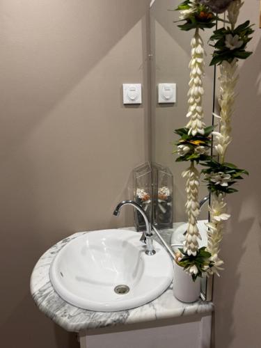 a bathroom sink with flowers on a counter at Hanivai Beach Bungalow in HUH