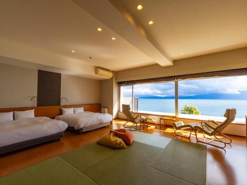 a bedroom with two beds and a large window at Kyukamura Ibusuki in Ibusuki
