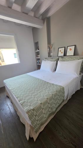 a bedroom with a large bed with white sheets and a window at Fantastica casa in stile mediterraneo - Al Ficodindia in Torre San Giovanni Ugento