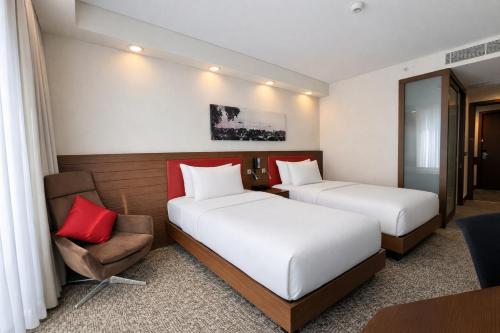 a hotel room with two beds and a chair at Hampton by Hilton Samsun in Samsun