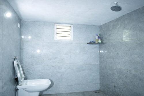 a bathroom with a white toilet and a window at Sindu Homestay in Kalasa
