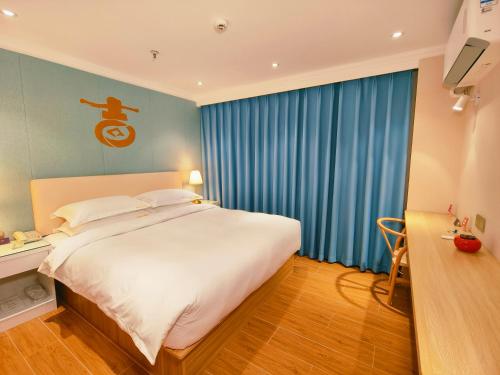 a bedroom with a large white bed and blue curtains at 福禄寿酒店 in Beiwusidui