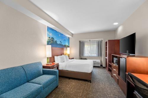 a hotel room with a bed and a blue couch at Clarion Pointe Starkville near University in Starkville