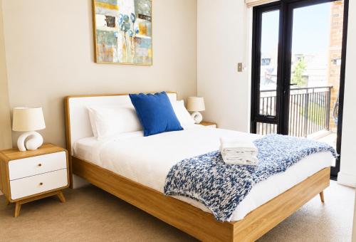 a bedroom with a bed with blue pillows and a window at Rooftops on HenryCentre of West End Cafes in Fremantle
