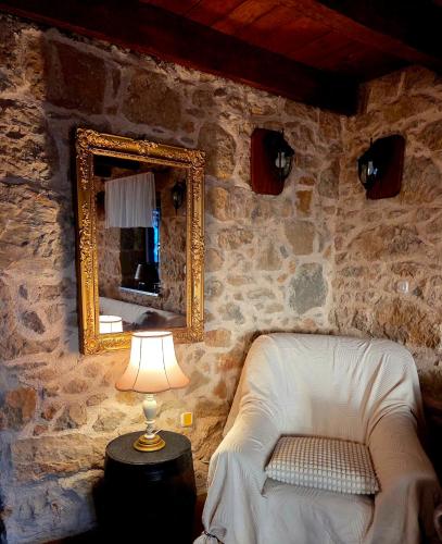 a mirror and a chair in a room with a lamp at Charming Stone House Dobrinj in Dobrinj