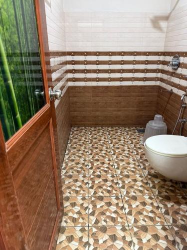 a bathroom with a shower and a toilet and a door at Staio Rooms in Thodupuzha
