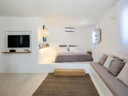 a white bedroom with a bed and a couch at myMykonos Guest House in Platis Gialos