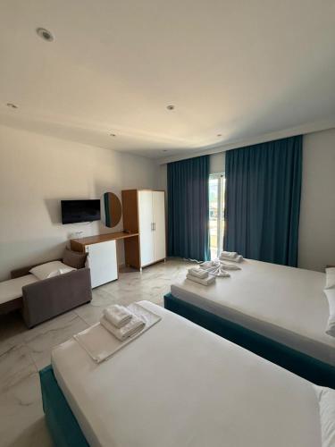 a hotel room with two beds and a television at Moonshine Hotel in Ksamil
