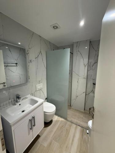 a white bathroom with a toilet and a sink at Moonshine Hotel in Ksamil