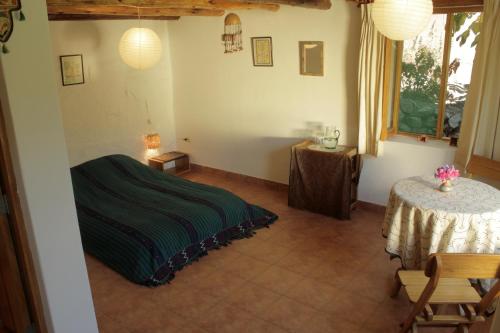 Un dormitorio con una cama verde y una mesa en Andean Spirit Lodge, en Limatambo