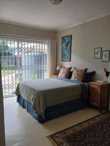 a bedroom with a bed and a large window at Dollery House in Port Alfred