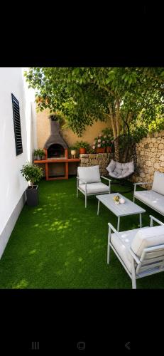 a patio with white tables and chairs and a fireplace at Apartman Donadina-Dalmatian heritage house in Trogir