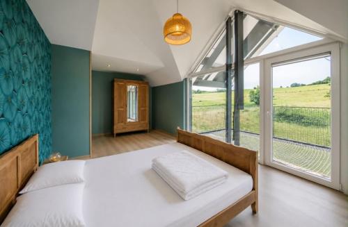 a bedroom with a bed and a large window at Au pachî d'Emile in Bièvre