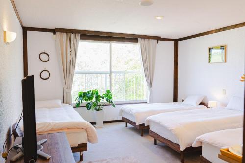 a bedroom with three beds and a tv and a window at REIBA STYLE Hotel in Nagasawa