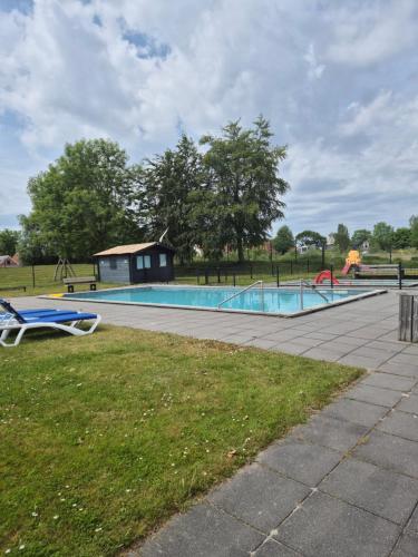 a swimming pool in a park with a playground at vacation home 68 in Tzummarum